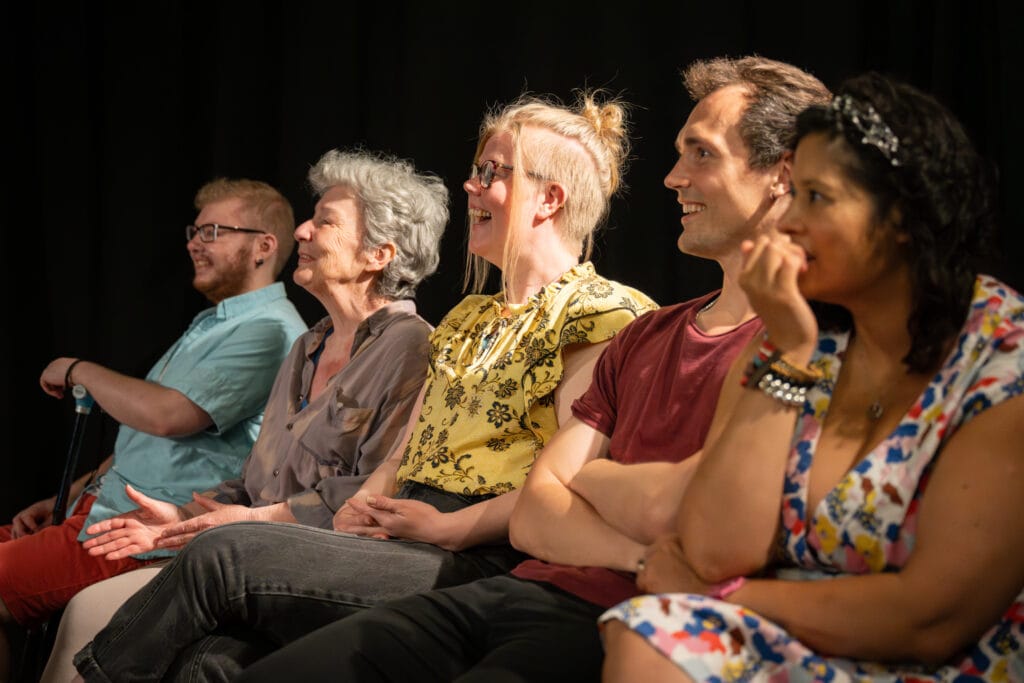 image shows small aroup of people sat in row. Smiling and laughing